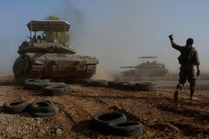 Un soldado israelí hace un gesto hacia un miembro de la tripulación de un tanque mientras cruza una carretera, como parte del convoy, en medio del conflicto en curso entre Israel y el grupo islamista palestino Hamas, cerca de la frontera de Israel con el sur de Gaza, en Israel, el 4 de diciembre de 2023.