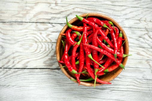 Red chili peppers in a bowl on wooden background