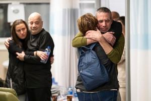 Los rehenes Fernando Simon Marman, derecha, y Luis Har, segundo desde la izquierda, abrazan a familiares después de ser rescatados del cautiverio en la Franja de Gaza, en el Centro Médico Sheba en Ramat Gan, Israel, el lunes 12 de febrero de 2024.