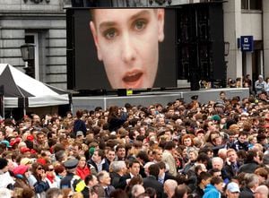 FILE PHOTO: A music video of Irish singer Sinead O'Connor plays over the crowd awaiting the arrival of U.S. President Barack Obama to speak at College Green in Dublin May 23, 2011.  REUTERS/Kevin Lamarque/File Photo