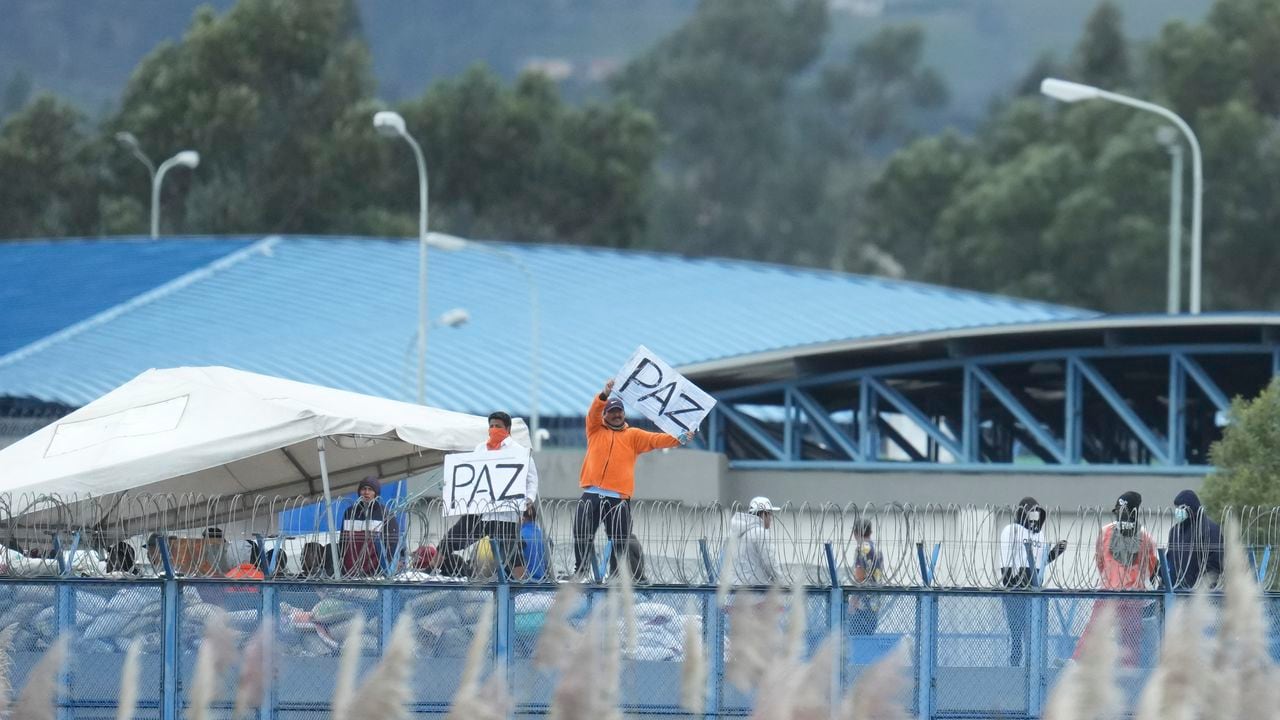 Los reclusos agitan carteles hechos a mano con la palabra española para la paz mientras están parados en la azotea de la prisión de Latacunga, oficialmente conocida como Centro de Rehabilitación Social Regional Sierra, Centro Norte, en Cotopaxi, Ecuador, el miércoles 10 de enero de 2024.