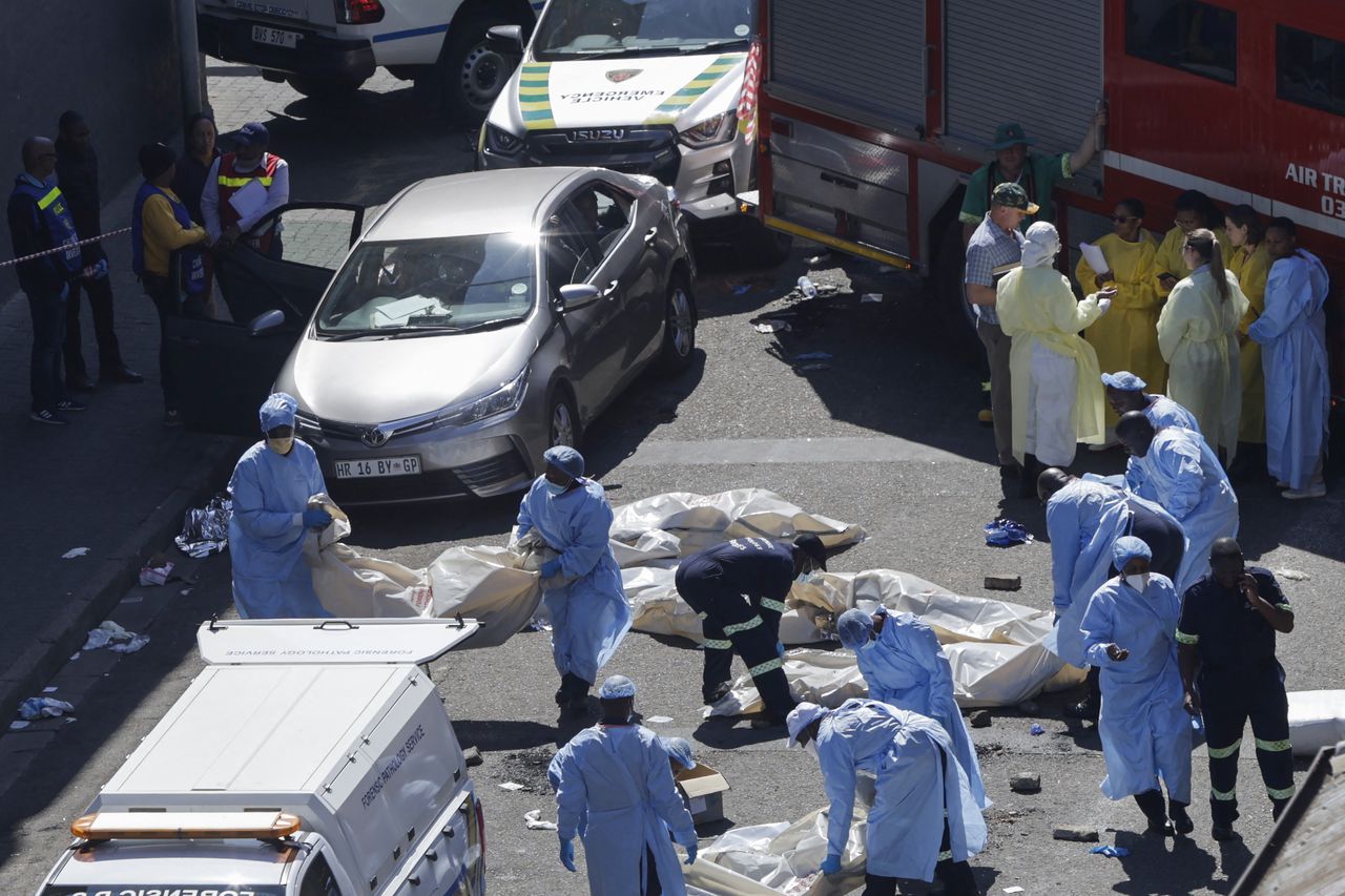 Miembros del departamento forense trasladan cadáveres en la escena de un incendio en Johannesburgo el 31 de agosto de 2023.