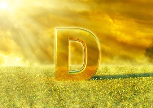 Vitamina D illuminated by the rays of the sun on grass. Sunlight is an excellent source of this nutrient that strengthens the immune system. 3D rendering