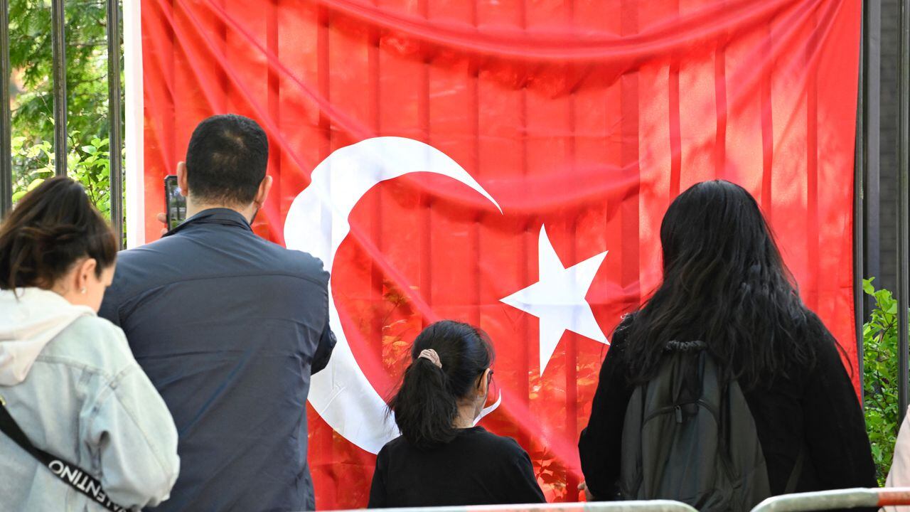 Los votantes turcos pasan una bandera turca mientras se dirigen al colegio electoral en el consulado turco en Berlín el 9 de mayo de 2023. Hay aproximadamente 1,5 millones de votantes turcos registrados que viven en Alemania, la diáspora más grande que participa en las elecciones más importantes de Turquía en décadas. . (Photo by Tobias SCHWARZ / AFP) / TO GO WITH AFP STORY BY FEMKE COLBORNE