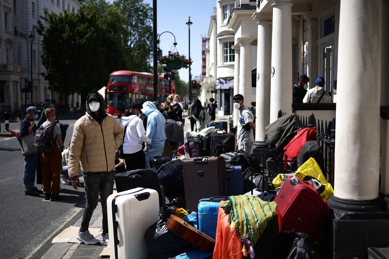 Un grupo de inmigrantes con su equipaje organiza una protesta frente a su alojamiento en el oeste de Londres el 2 de junio de 2023, mientras se quejan de las condiciones de vida.