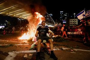 Un manifestante se sienta mientras surge el fuego durante una manifestación contra el primer ministro israelí Benjamin Netanyahu y la revisión judicial de su gobierno de coalición nacionalista, en Tel Aviv, Israel, el 20 de julio de 2023. 