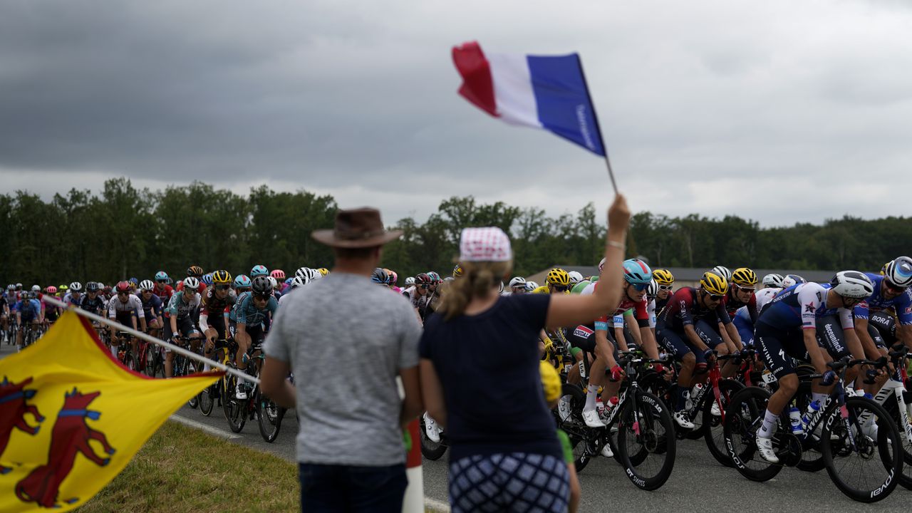 Los espectadores saludan el paso del pelotón del Tour de Francia durante la 19na etapa, el viernes 22 de julio de 2022.