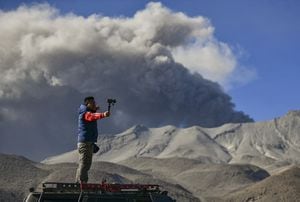A man takes a selfie picture as a smoke and ash stack rises from the Ubinas volcano's crater, located in the Moquegua region in southern Peru, on July 5, 2023. Peru's Ubinas volcano, active again after four dormant years, blew its top twice on July 4, showering nearby towns with ash, the country's IGP geophysical institute said. (Photo by Diego Ramos / AFP)