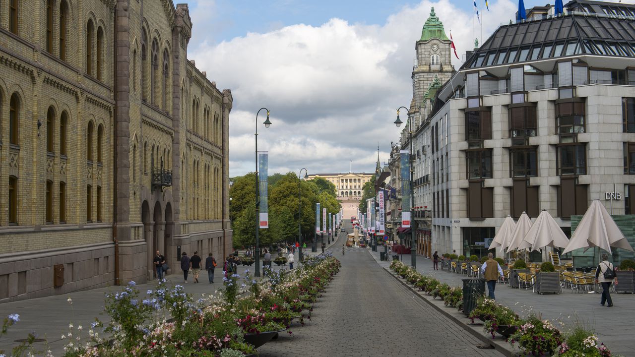 Escena callejera de Karl Johans Gate en Oslo, Noruega, con el palacio real al fondo