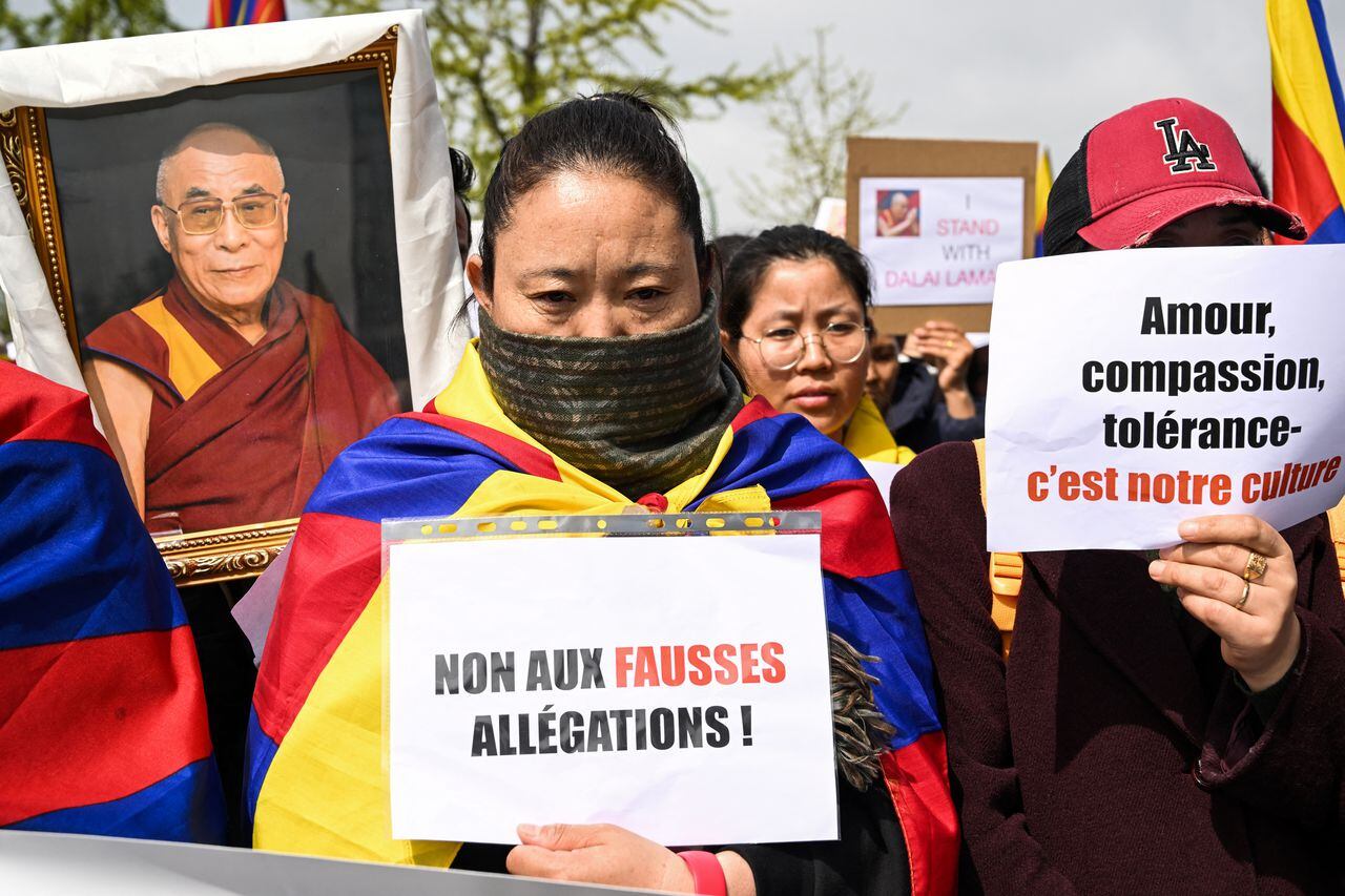 Una mujer sostiene un cartel que dice "No a las acusaciones falsas" durante una manifestación en apoyo del líder espiritual tibetano, el Dalai Lama.