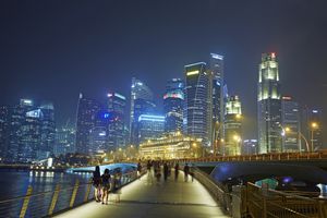 Línea de rascacielos en el distrito financiero de Singapur y Marina Bay iluminada por la noche.