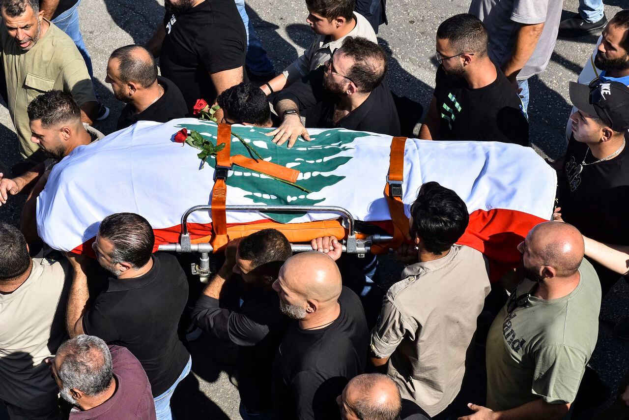 Los dolientes llevan el ataúd cubierto con la bandera del videoperiodista libanés de Reuters Issam Abdallah, asesinado el 13 de octubre por bombardeos israelíes en la aldea fronteriza de Alma al-Shaab con Israel mientras cubría bombardeos transfronterizos, durante su funeral en la aldea de El-Khiam el 14 de octubre. , 2023. Abdallah fue asesinado el 13 de octubre y otras seis personas de AFP, Reuters y Al Jazeera resultaron heridas mientras trabajaban en el sur del Líbano, dijeron las tres organizaciones de noticias. (Photo by Fadel ITANI / AFP)