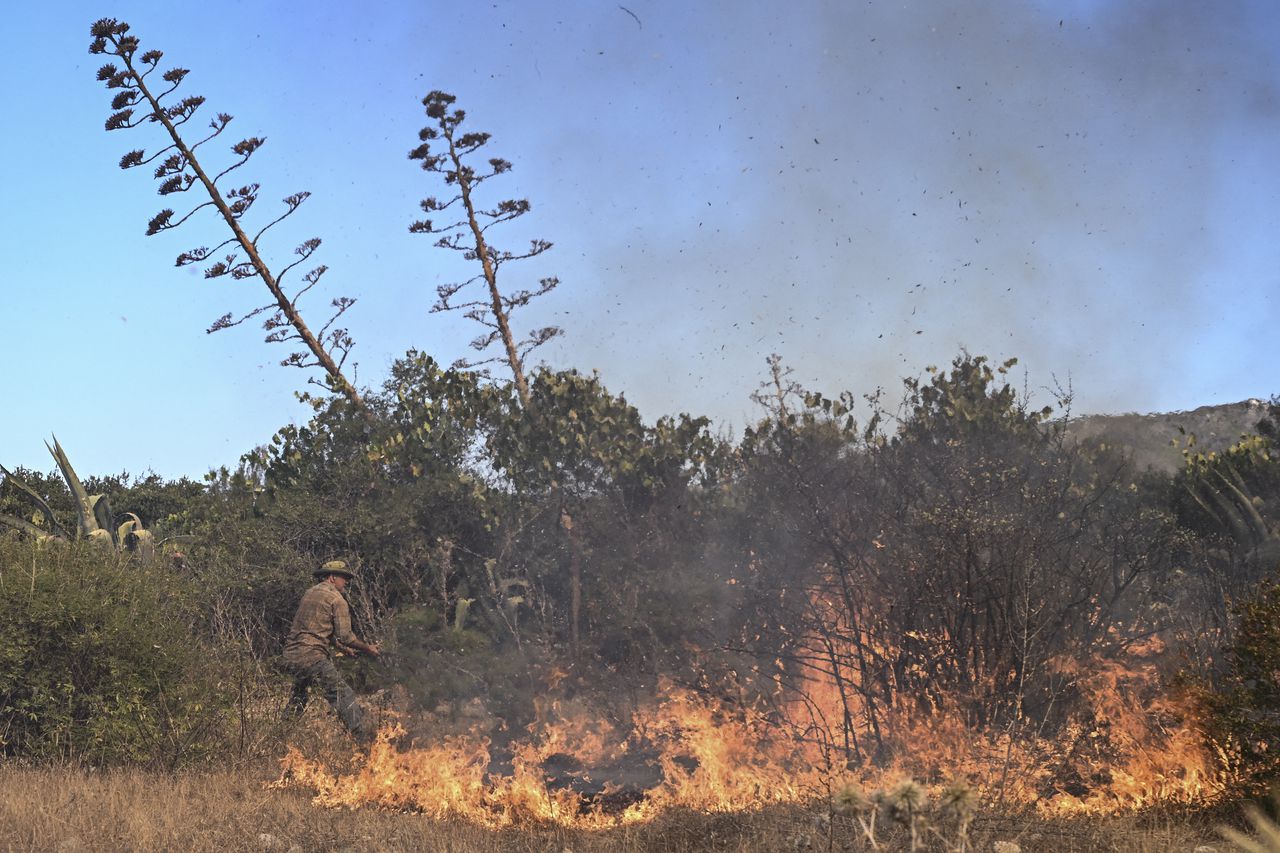Un lugareño usa la rama de un árbol para apagar las llamas de un incendio forestal cerca de la aldea de Vati, justo al norte de la ciudad costera de Gennadi, en la parte sur de la isla griega de Rodas el 25 de julio de 2023.