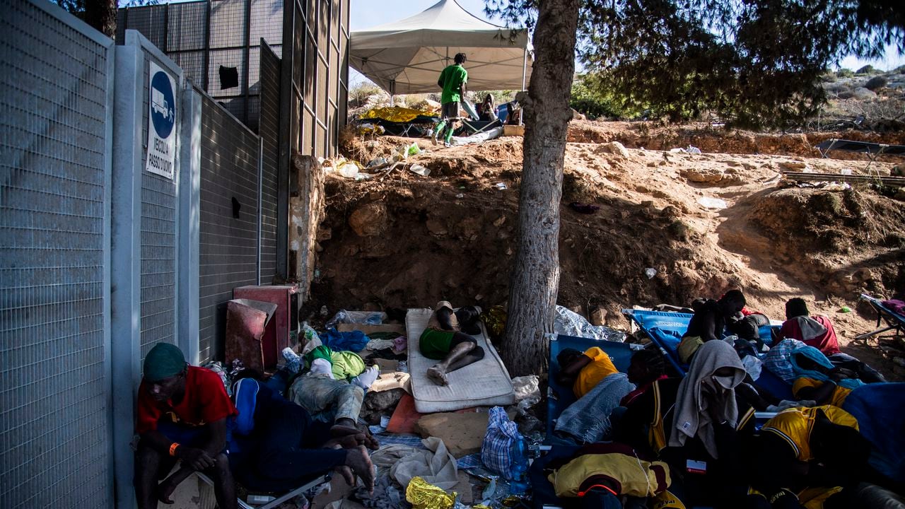 Los migrantes se reúnen frente al centro operativo llamado "Hotspot" en la isla italiana de Lampedusa el 15 de septiembre de 2023. El centro de recepción de la isla, construido para albergar a menos de 400 personas, estaba abrumado por hombres, mujeres y niños obligados a dormir al aire libre sobre plástico improvisado. catres, muchos de ellos envueltos en mantas metálicas de emergencia. El buen tiempo ha provocado un aumento en las llegadas a Italia en los últimos días: más de 5.000 personas desembarcaron en todo el país el 12 de septiembre y casi 3.000 el día siguiente, según cifras actualizadas del Ministerio del Interior.
