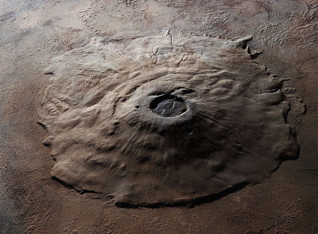 En los confines del sistema solar, un prodigio geológico desafía los límites de lo conocido, emergiendo de las llanuras polvorientas de Marte con una majestuosidad sin igual.