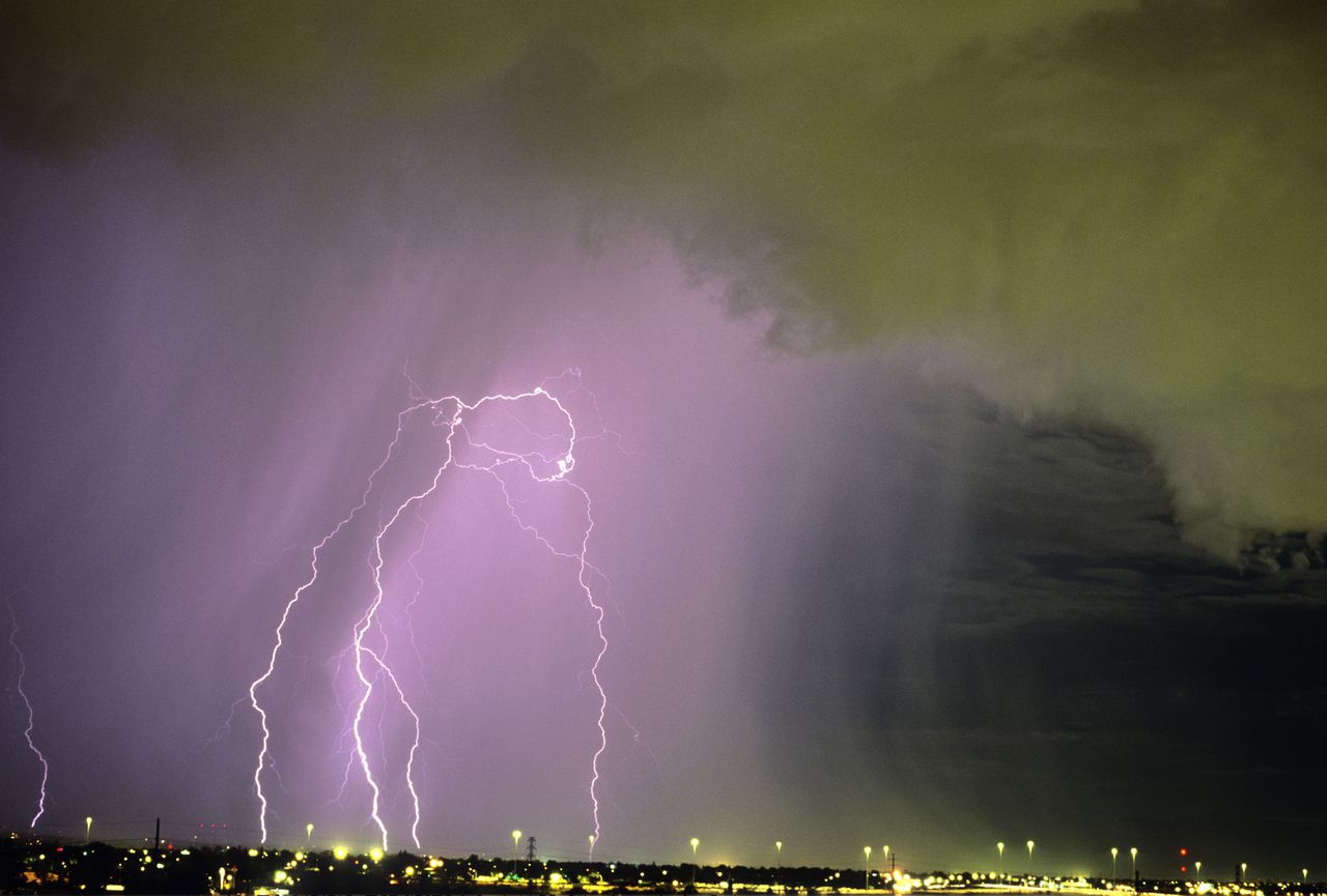 Célula de tormenta activa sobre la ciudad con nubes en primer plano y una cortina de lluvia detrás, que contiene múltiples descargas de rayos de nube a tierra, Tucson, Arizona, EE. UU.