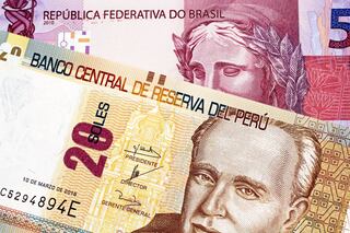 A macro image of a twenty Peruvian soles bank note with a purple Brazilian five reais bill