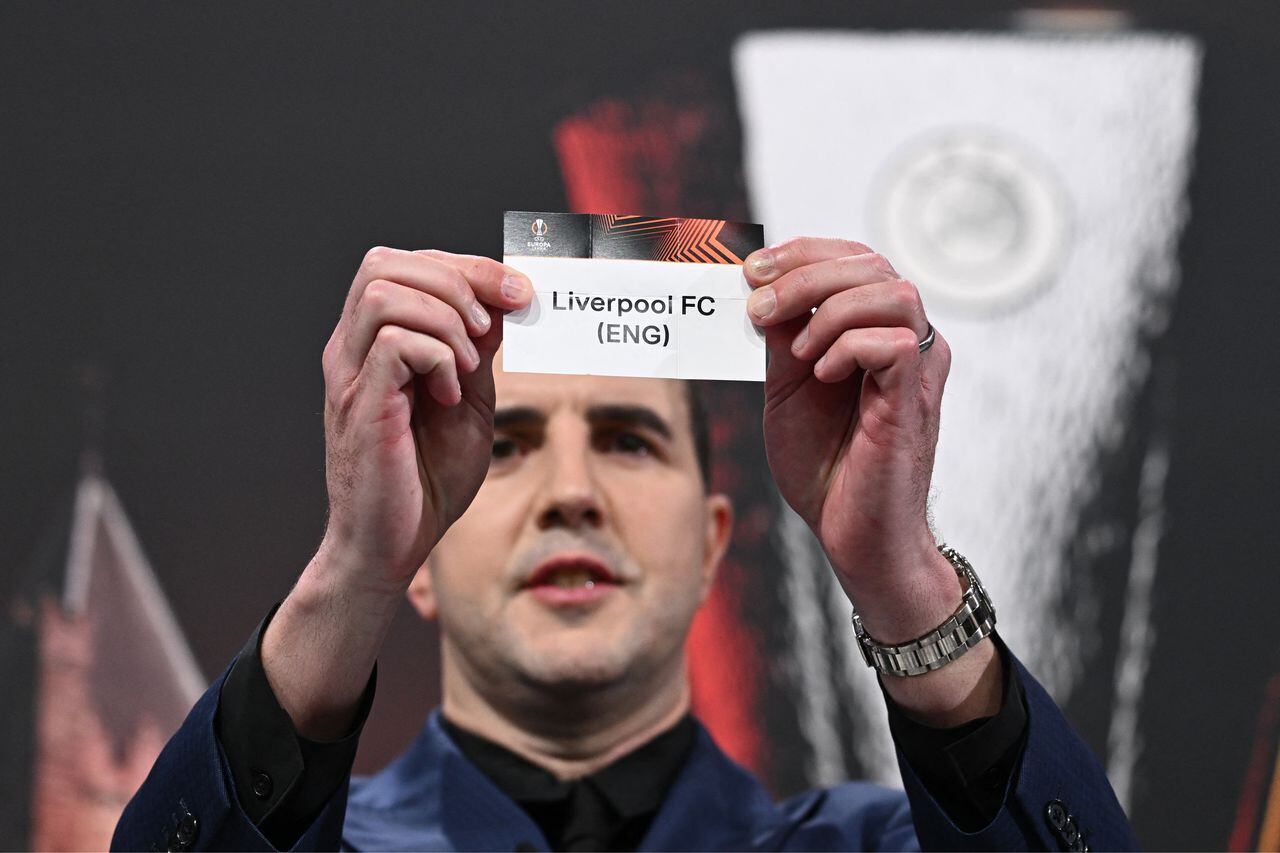 Irish former football international John O'Shea holds up the paper slip of Liverpool FC during the draw for the round of 16 of the 2023-2024 UEFA Europa League football tournament at the House of European Football in Nyon, on February 23, 2024. (Photo by Fabrice COFFRINI / AFP)