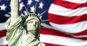 Estatua de la libertad con la bandera americana borrosa ondeando en el fondo. Getty Images.