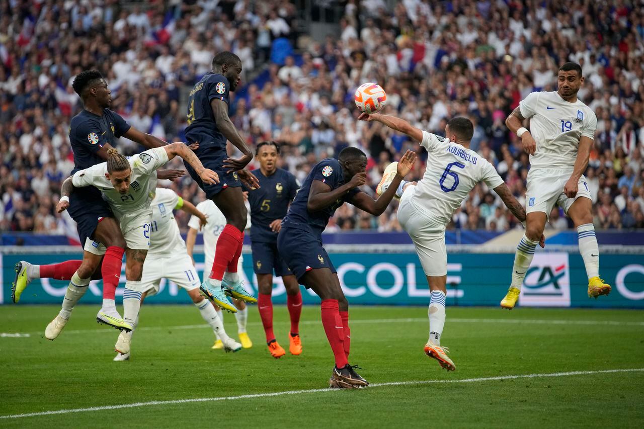 El francés Dayot Upamecano, centro izquierda, cabecea el balón durante el partido clasificatorio del grupo B para la Eurocopa 2024 entre Francia y Grecia en el Stade de France, en las afueras de París, el lunes 19 de junio de 2023. (Foto AP/Christophe Ena)