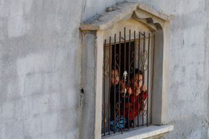 Los niños miran desde una ventana mientras los dolientes asisten al funeral del palestino Mohammed Abu Eteyma, quien murió en un ataque israelí, en Khan Younis, en el sur de la Franja de Gaza, el 10 de mayo de 2023.