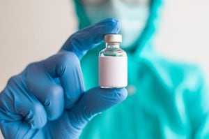 A female healthcare worker in vibrant colored protective suit is holding a medicine vial