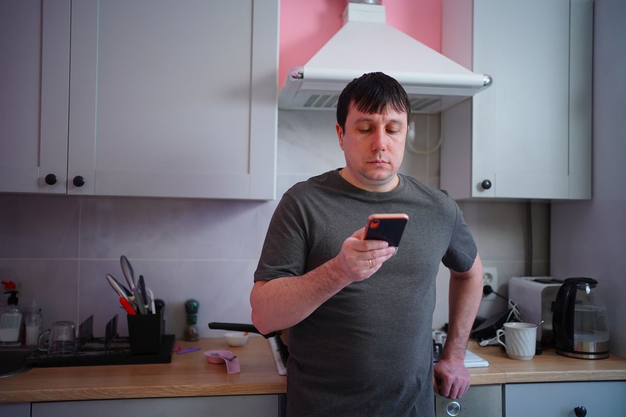 father searches his smartphone for a recipe for cooking