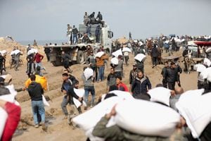 Los palestinos cargan bolsas de harina que agarraron de un camión de ayuda cerca de un puesto de control israelí, mientras los residentes de Gaza enfrentan niveles críticos de hambre, en medio del conflicto en curso entre Israel y Hamás, en la ciudad de Gaza, el 19 de febrero de 2024.