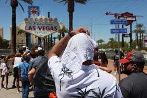 Hombre se protege del sol mientras espera en la fila para tomar una foto en el histórico cartel de Bienvenido a Las Vegas durante una ola de calor en Las Vegas, Nevada, el 14 de julio de 2023.