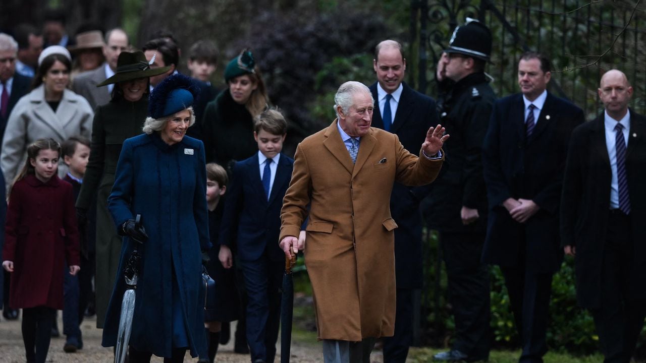 (FILES) Britain's King Charles III (R) flanked by Britain's Camilla, Queen Consort (L) waves to members of the public as he arrives for the Royal Family's traditional Christmas Day service at St Mary Magdalene Church in Sandringham, Norfolk, eastern England, on December 25, 2022. Britain's Charles III reaches the milestone of his first year as king this week, with his reign so far characterised by a smooth transition from that of his late mother, Queen Elizabeth II. (Photo by Daniel LEAL / AFP)