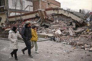 People walk past a collapsed building after an earthquake in Dahejia, Jishishan County in northwest China�s Gansu province on December 19, 2023. (Photo by Pedro Pardo / AFP)