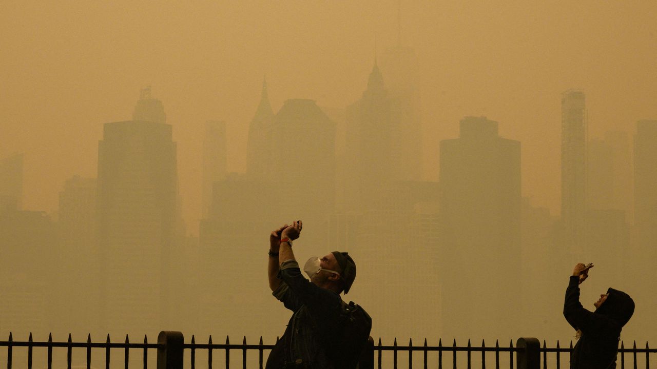 La gente toma fotos del sol mientras el humo de los incendios forestales en Canadá provoca condiciones de niebla en la ciudad de Nueva York el 7 de junio de 2023.