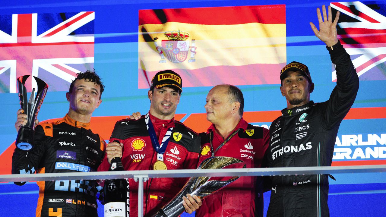 El ganador de la carrera, el piloto de Ferrari Carlos Sainz de España, segundo a la izquierda, junto con el segundo clasificado de McLaren, Lando Norris de Gran Bretaña, a la izquierda, y el tercer clasificado de Mercedes, Lewis Hamilton de Gran Bretaña, a la derecha, en el podio con un compañero de Ferrari después del Gran Premio de Fórmula 1 de Singapur. Premio en el circuito de Marina Bay, Singapur, domingo 17 de septiembre de 2023. (Foto AP/Vincent Thian)