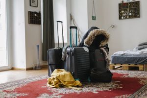 Some holiday goers luggage and belongings in the middle of the living room in a rental property.