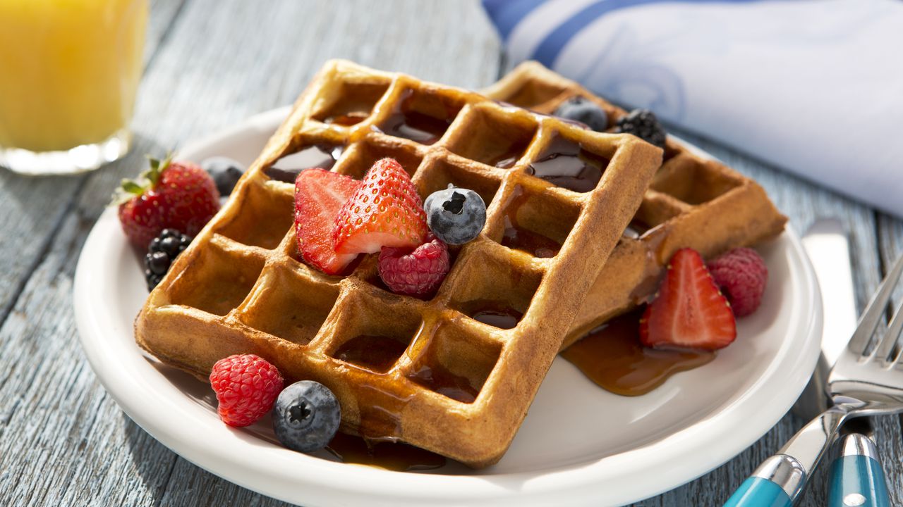 Waffles saludables para el desayuno con mezcla de toppings nutritivos como fresas y arándanos.