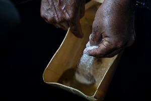 Un trabajador rocía soda caucásica sobre agua con alcaloide de coca en un "laboratorio" donde las hojas de coca se procesan en pasta de coca