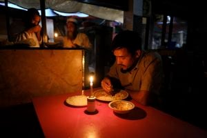 Una persona come en un restaurante a la luz de las velas durante un corte de energía en Dhaka, Bangladesh. 4 de octubre de 2022. Una falla en la red de suministro de energía nacional de Bangladesh sumió a la mayor parte del país en un apagón el martes, dijeron las autoridades. (AP Photo/Mahmud Hossain Opu)