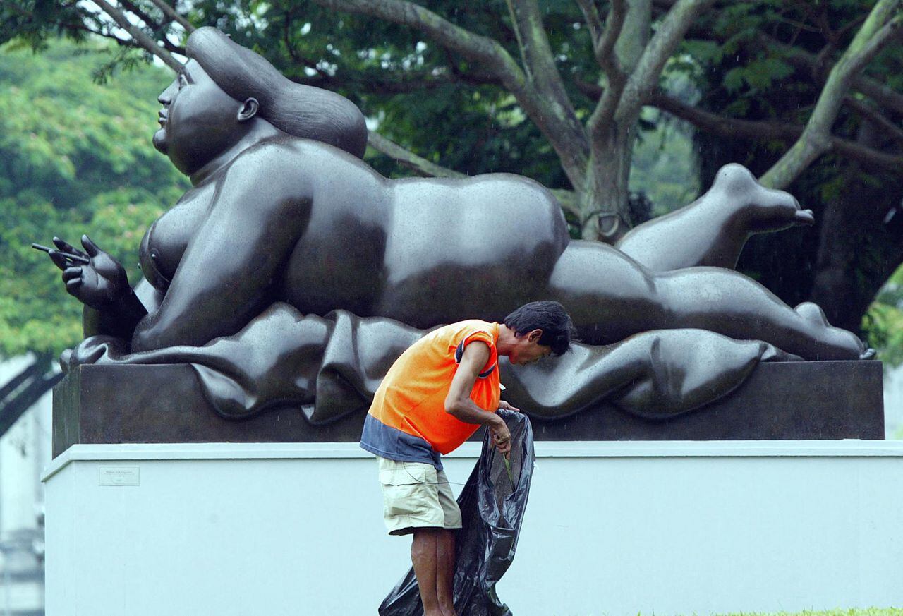 Un trabajador recoge basura alrededor de la escultura de Botero de una "mujer gorda con un cigarrillo" exhibida en un parque en Singapur, el 6 de diciembre de 2004.