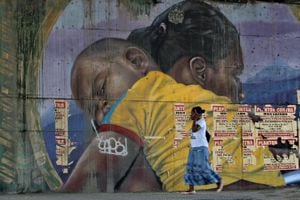 Una mujer pasa frente a un mural en el centro de Cali.