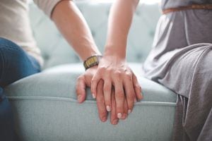 Waist photo of man and woman holding hands while sitting on a couch