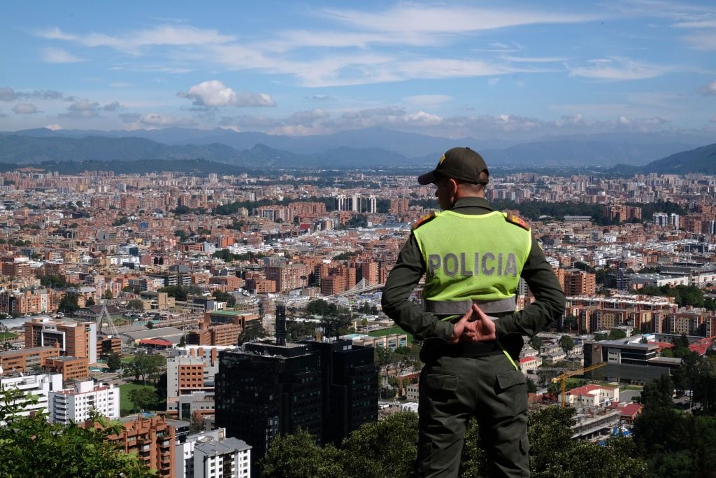 BOGOTA, COLOMBIA - JANUARY 12, 2017: A policeman on duty stands with Bogota's skyline in the background on the spot known as "Mirador de la Paloma" on La Calera road or better known as "Mirador de La Calera" on January 12, 2017 in Bogota, Colombia. This Mirador is very well known to Colombians and foreign tourists for its view over Bogota and the romantic evenings spent there. (Photo by Kaveh Kazemi/Getty Images)