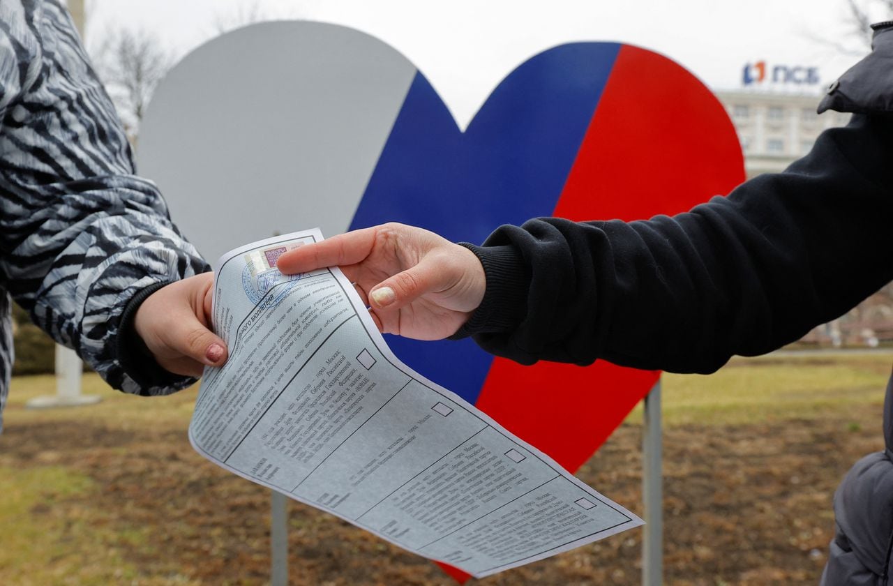 Un miembro de una comisión electoral local entrega una papeleta a un votante en un colegio electoral móvil durante la votación anticipada de las elecciones presidenciales de Rusia, en el curso del conflicto Rusia-Ucrania en Donetsk, Ucrania controlada por Rusia, el 14 de marzo de 2024.