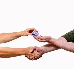 Hand handing over Colombian money - White background