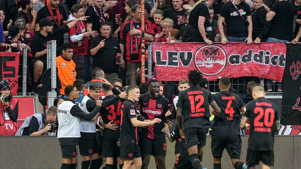 Victor Boniface (centro) celebra junto a sus compañeros del Bayer Leverkusen luego del tercer gol de su equipo ante el Colonia en partido de la Liga Alemana en el BayArena en Leverkusen, Alemania, el domingo 8 de octubre de 2023. (AP Foto/Martin Meissner)