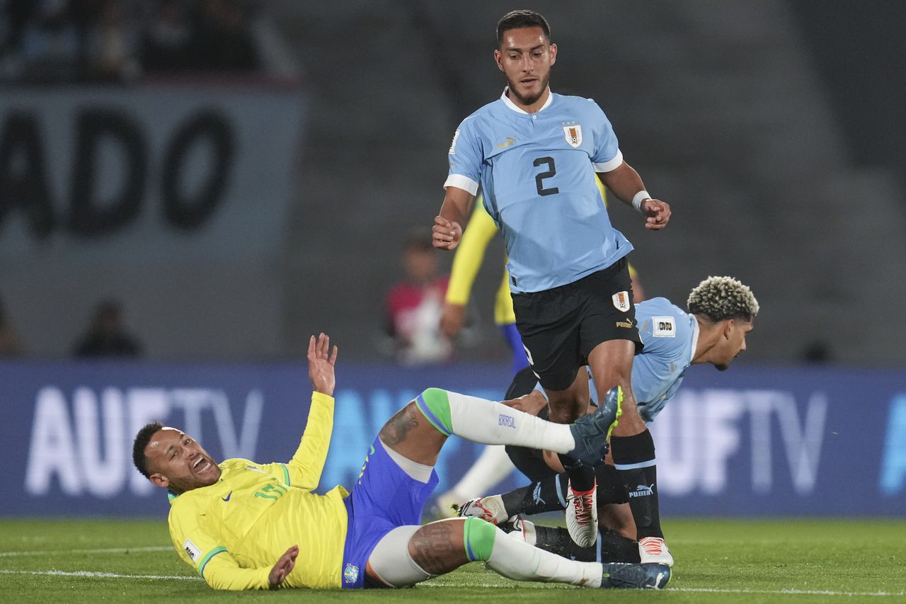 Brazil's Neymar falls while fighting for a ball with Uruguay's Sebastian Caceres during a qualifying soccer match for the FIFA World Cup 2026 at Centenario stadium in Montevideo, Uruguay, Tuesday, Oct. 17, 2023. (AP Photo/Matilde Campodonico)