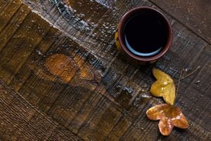 Taza de café negro y hojas de otoño sobre una vieja mesa de madera húmeda. plano