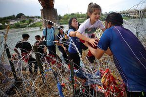 Migrantes de Venezuela atraviesan el alambre de púas después de cruzar el Río Grande hacia los Estados Unidos en Eagle Pass, Texas, EE. UU., el 26 de septiembre de 2023.