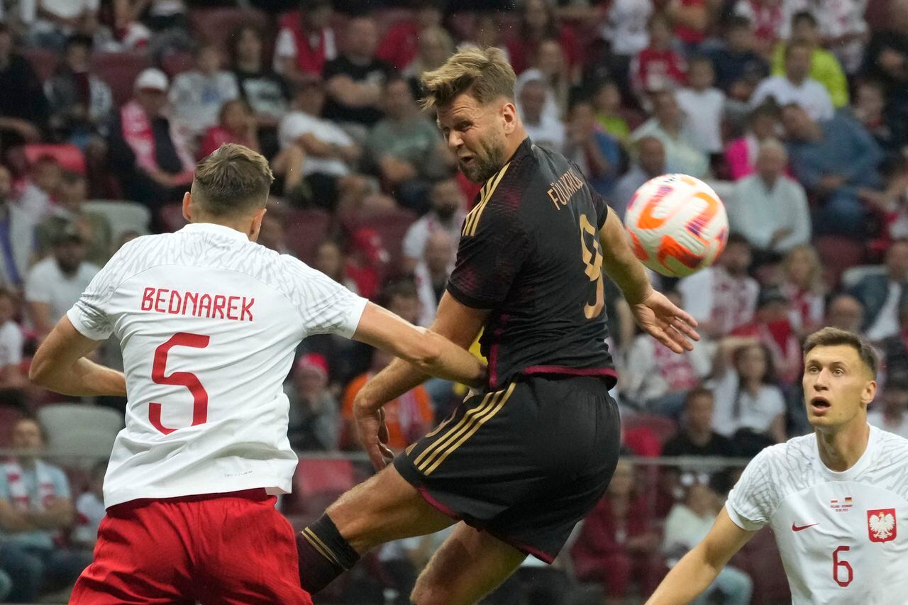 El polaco Jan Bednarek, a la izquierda, desafía el balón con el alemán Niclas Fullkrug durante el partido amistoso de fútbol internacional entre Polonia y Alemania en el estadio Narodowy en Varsovia, Polonia, el viernes 16 de junio de 2023. (Foto AP/Czarek Sokolowski)