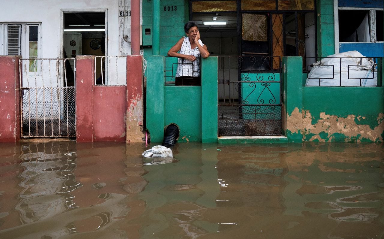 Una mujer se encuentra frente a su casa en un área inundada de Batabano, provincia de Mayabeque, Cuba, el 28 de agosto de 2023, mientras la tormenta tropical Idalia se acerca al extremo occidental de la nación insular.