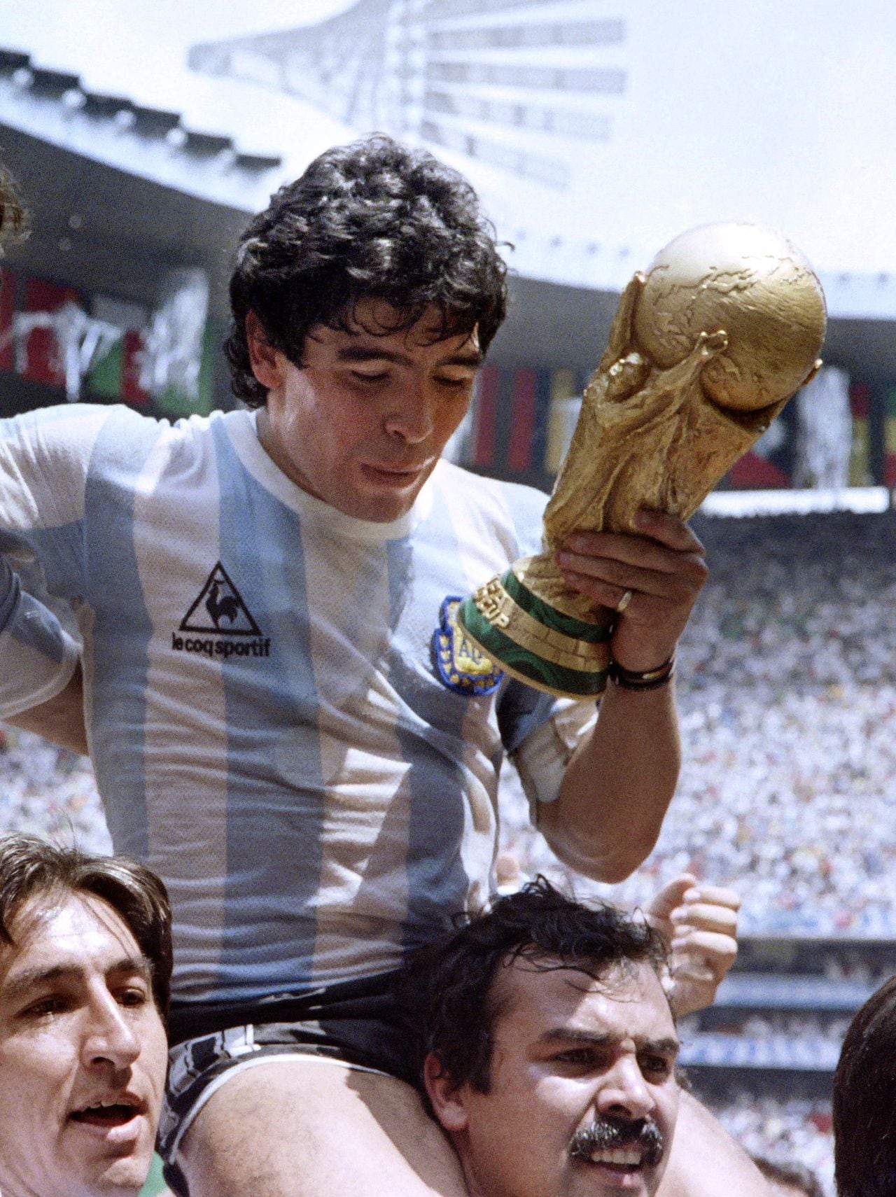 Argentina's forward Diego Maradona is carried on the shoulders of fans as he does a victory lap holding the FIFA World Cup after Argentina defeated West Germany 3-2 in the World Cup final on June 29, 1986 in Mexico City. (Photo by STAFF / AFP)